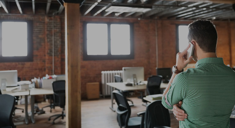 Man taking a call as he observes office space